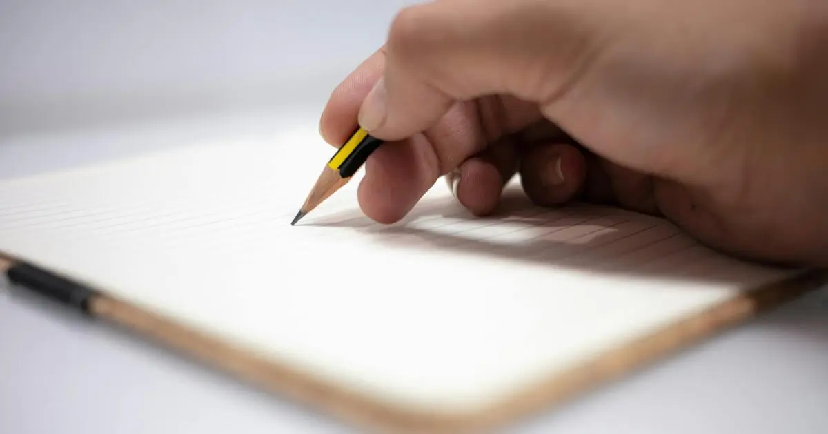 貯金や投資の計画を立てるためにノートへ書き込む手元の様子